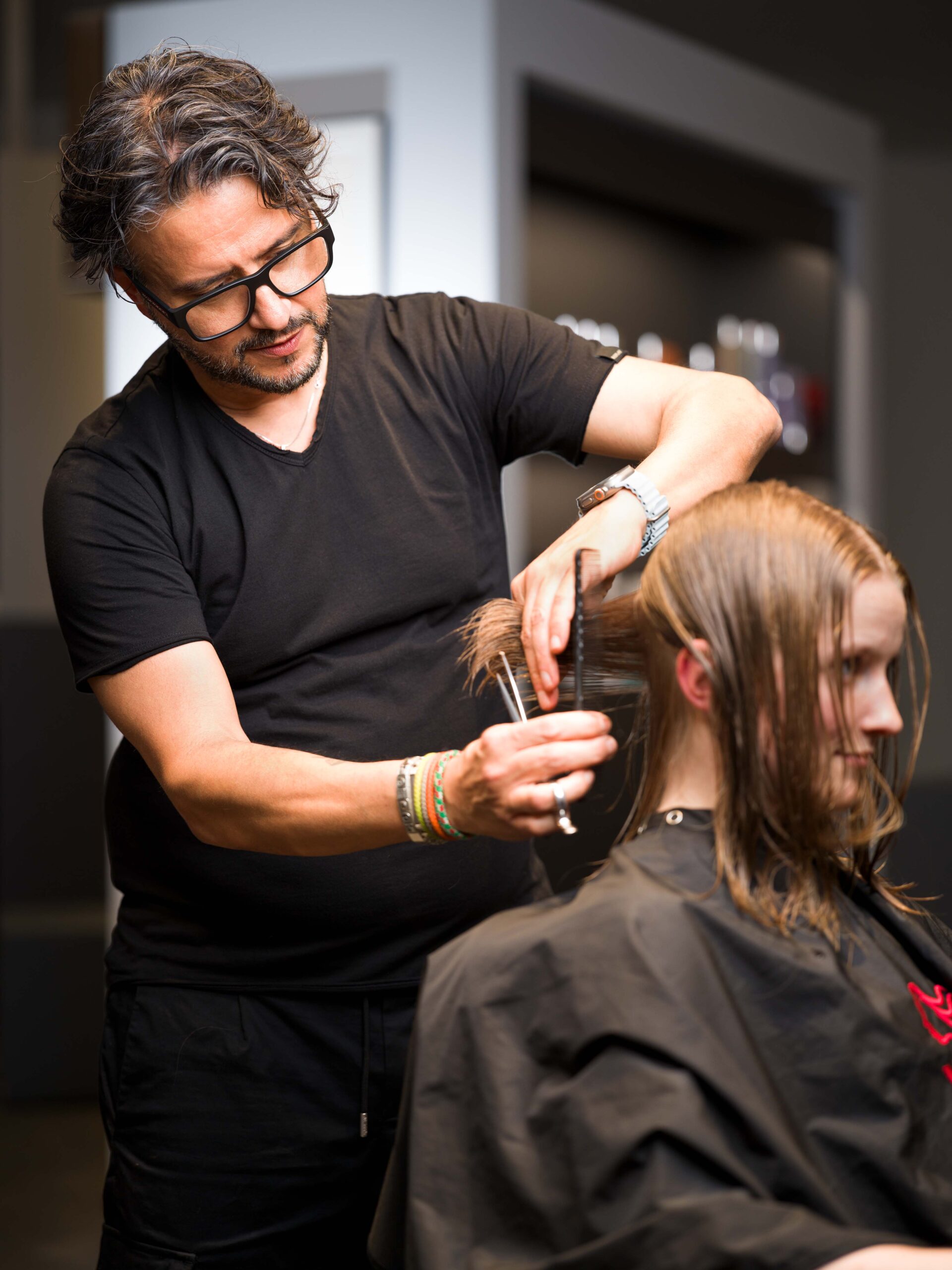Rocco Coroneo schneidet als Friseur einer blonden Dame die Haare mit einer Schere in seinem Salon