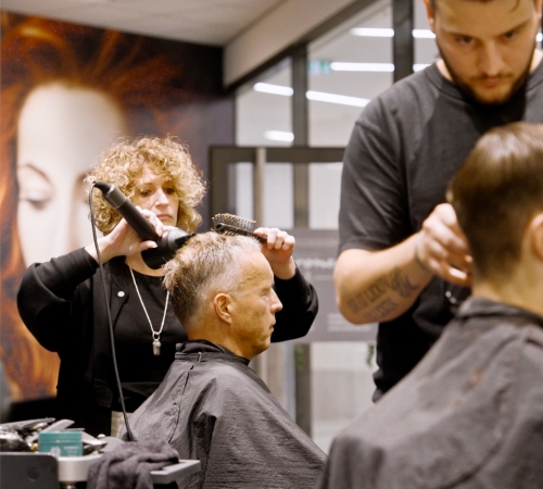 Leistungen Friseur Erkrath. Mitarbeiterin von Coroneo Hair Design in Erkrath frisiert einem Herren die Haare